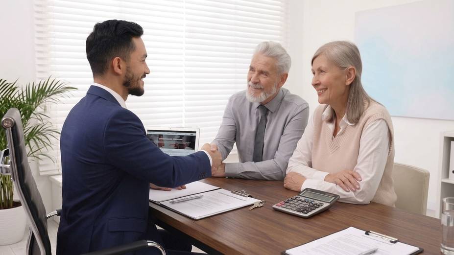 Advogado cumprimentando com atenção um casal de clientes idosos